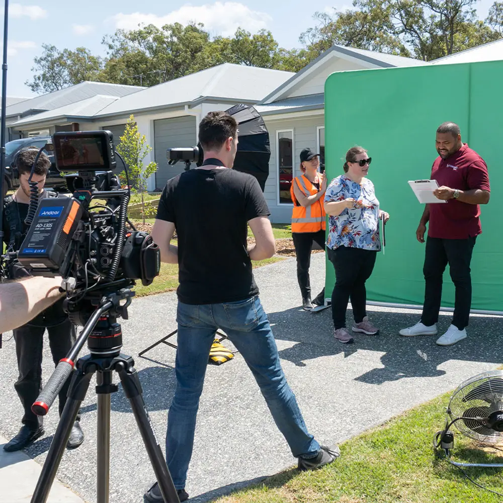 The Video Box team on set with Sam Thaiday for a Catapult Homes campaign, featuring a camera operator, sound producer, still photographer, and green screen setup.